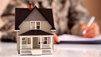 Soldier in uniform signing lease with superimposed house in the foreground