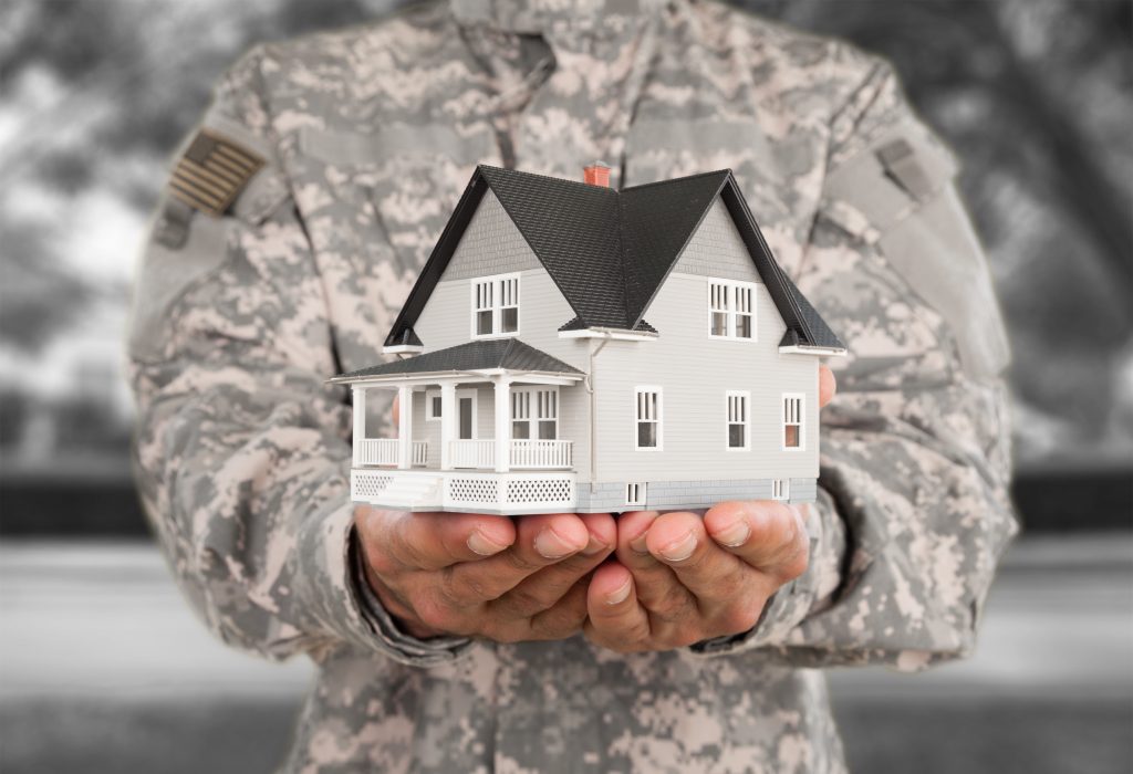 Man in US military uniform holding mock-up of house