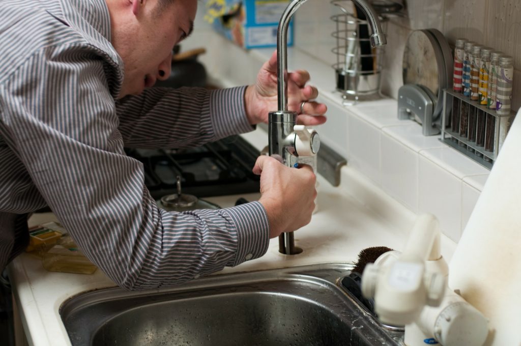 Plumber working for a home warranty company fixing a sink faucet.