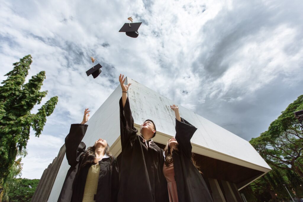 Three students graduating throwing caps.