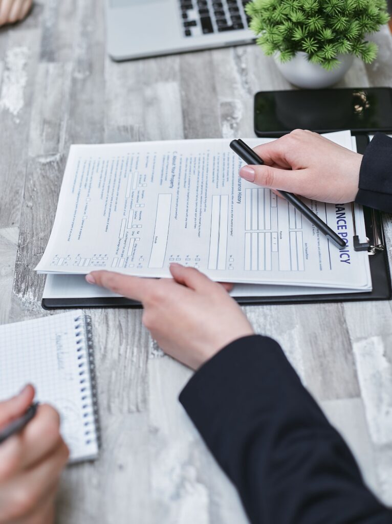 Two people reviewing and signing a renters insurance policy document on a clipboard